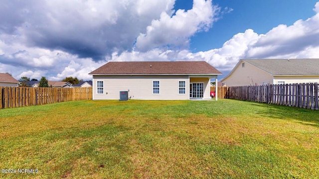 rear view of property with a fenced backyard, a yard, and central AC unit