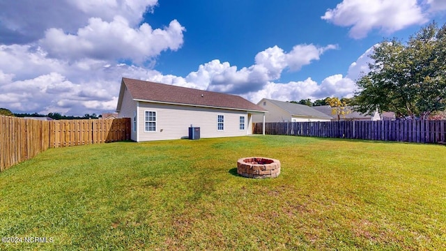 back of house featuring an outdoor fire pit, a lawn, and a fenced backyard