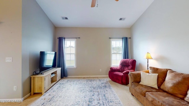 living area featuring light carpet, plenty of natural light, visible vents, and a ceiling fan