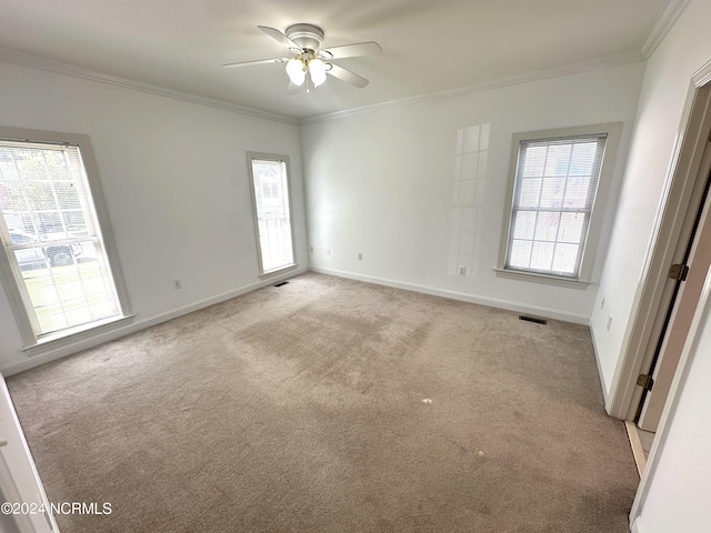 spare room with a wealth of natural light, visible vents, crown molding, and light carpet