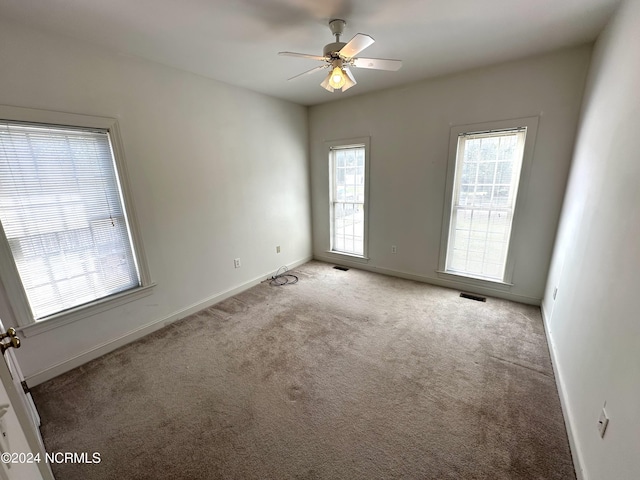 carpeted spare room with a ceiling fan, baseboards, and visible vents