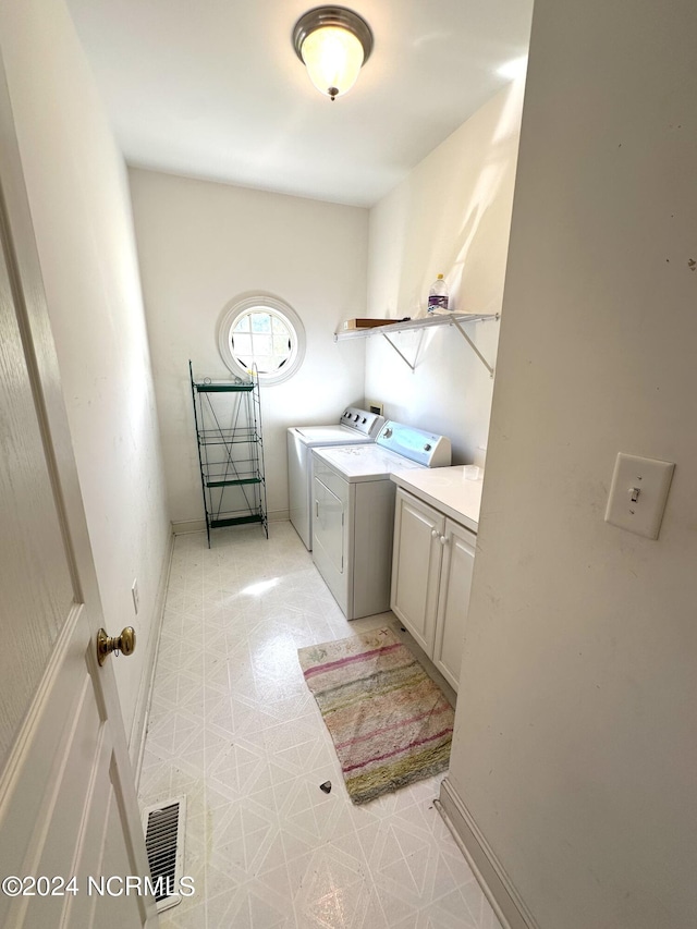 laundry area featuring washing machine and clothes dryer, visible vents, baseboards, light floors, and cabinet space