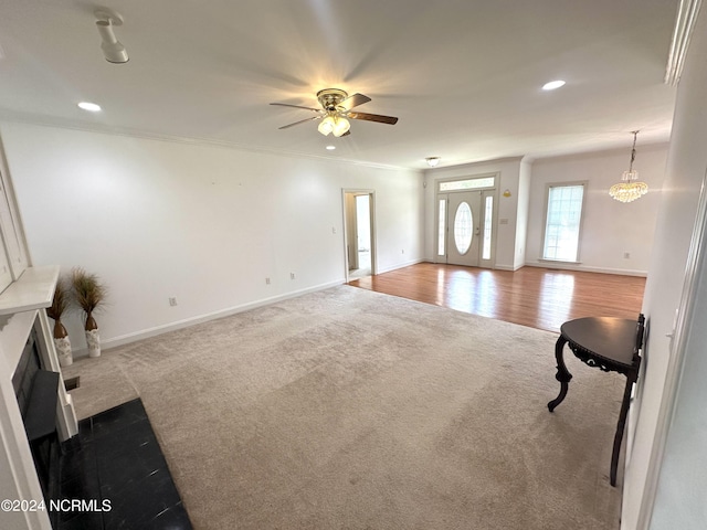 living room with ceiling fan with notable chandelier, light hardwood / wood-style floors, and ornamental molding