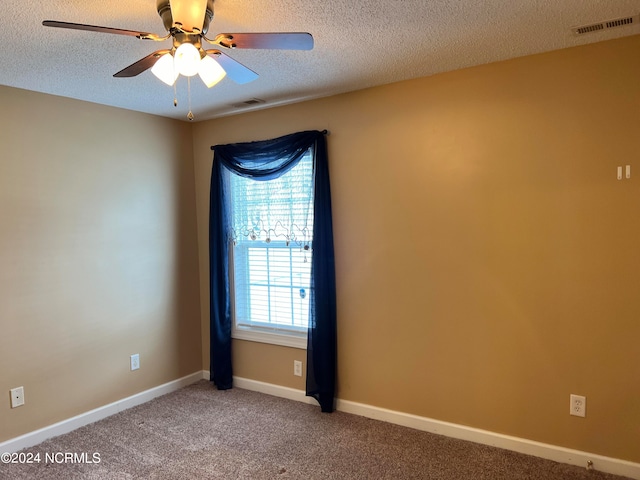 empty room featuring ceiling fan, a textured ceiling, and carpet