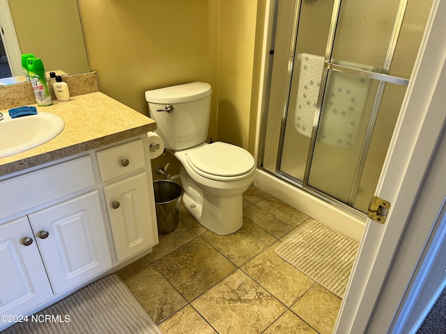 bathroom with vanity, toilet, and a shower with door