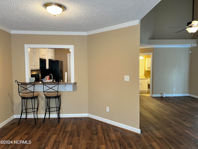 interior space featuring crown molding, white cabinets, dark wood-type flooring, and a breakfast bar