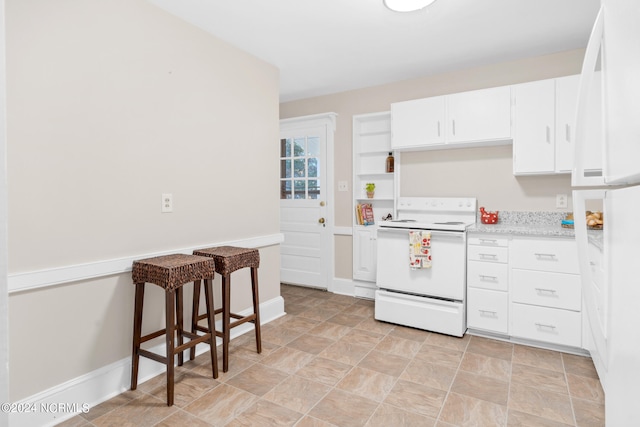 kitchen with white range with electric stovetop, a kitchen bar, and white cabinetry