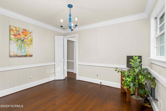 empty room with a notable chandelier, crown molding, wooden walls, and dark hardwood / wood-style flooring