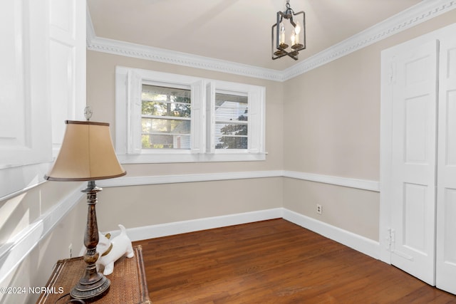 empty room featuring ornamental molding, an inviting chandelier, and hardwood / wood-style floors