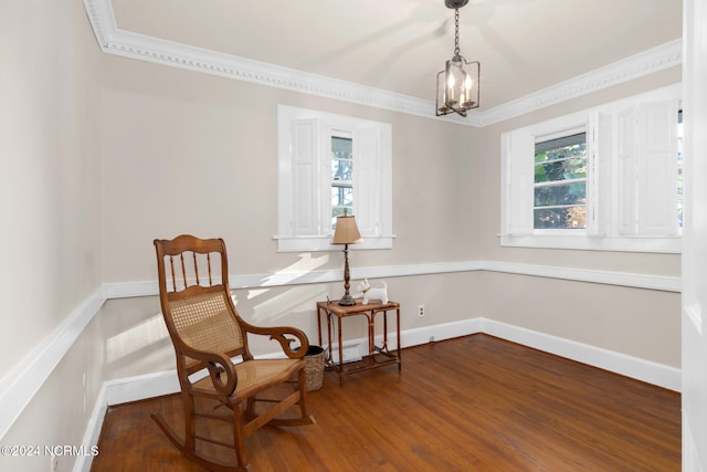 living area featuring crown molding, hardwood / wood-style floors, and an inviting chandelier