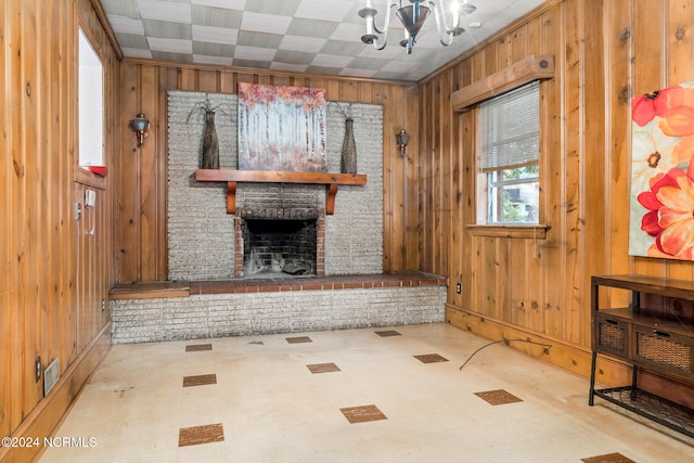 unfurnished living room featuring a notable chandelier, a fireplace, and wood walls