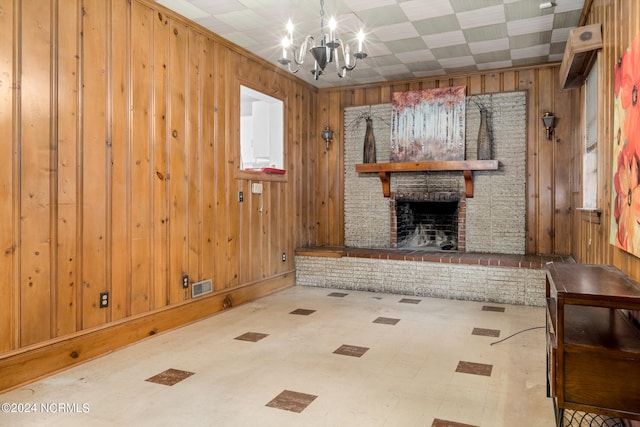 unfurnished living room featuring wooden walls, a fireplace, and an inviting chandelier