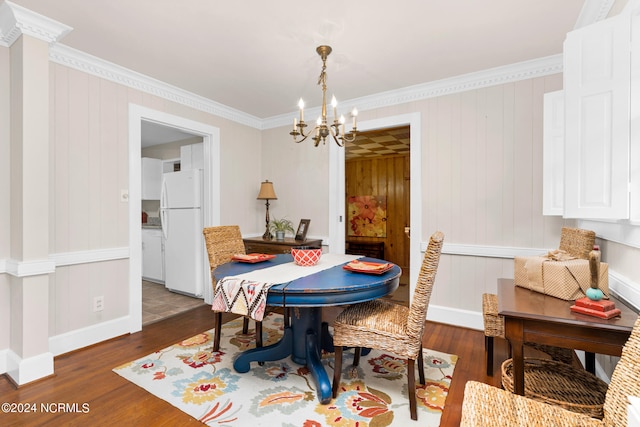 dining area with ornamental molding, an inviting chandelier, wood walls, and dark hardwood / wood-style flooring