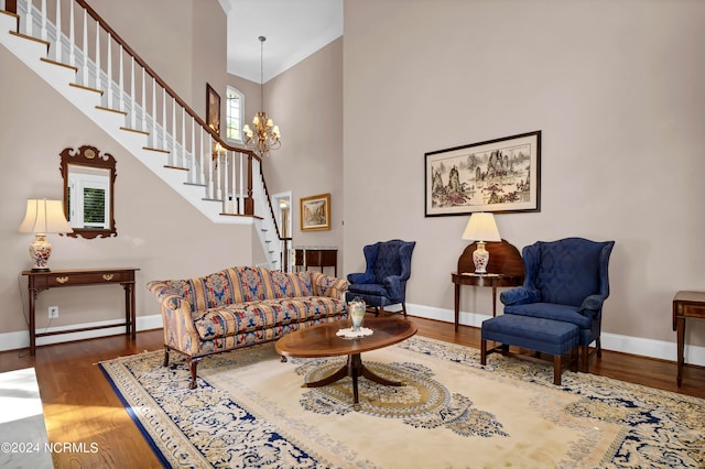 living room featuring dark wood-type flooring, crown molding, a notable chandelier, and a towering ceiling