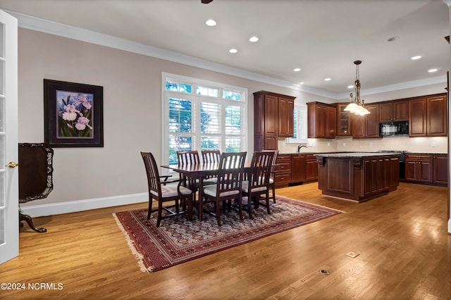 dining area with light hardwood / wood-style flooring, ornamental molding, and sink