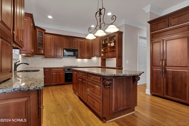 kitchen featuring hanging light fixtures, black appliances, a center island, crown molding, and light hardwood / wood-style floors