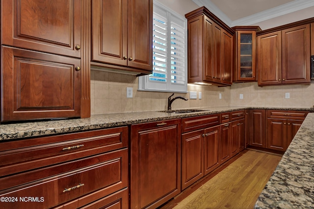 kitchen featuring tasteful backsplash, light stone countertops, sink, light hardwood / wood-style floors, and crown molding