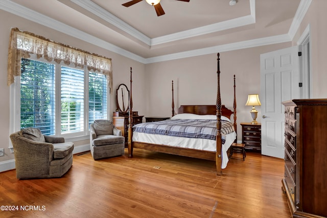 bedroom featuring crown molding, hardwood / wood-style floors, a tray ceiling, and ceiling fan