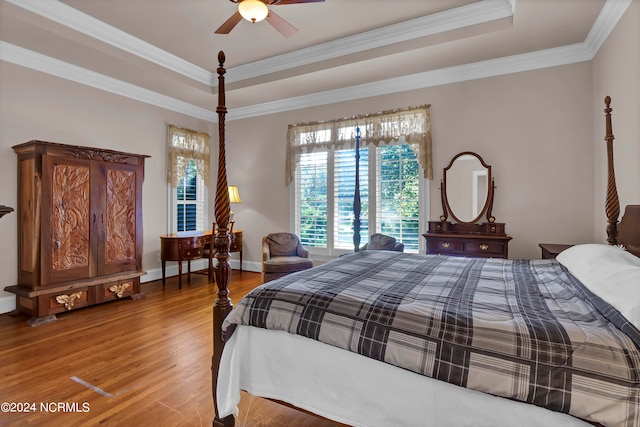 bedroom featuring ornamental molding, hardwood / wood-style flooring, a tray ceiling, and ceiling fan