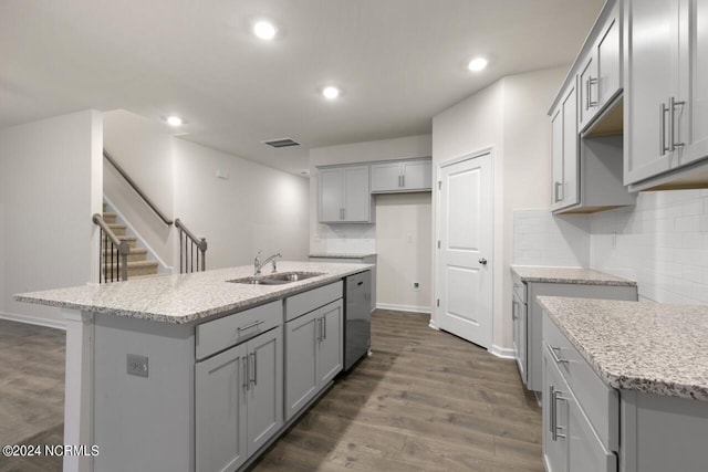 kitchen with dark hardwood / wood-style flooring, dishwasher, a kitchen island with sink, and sink