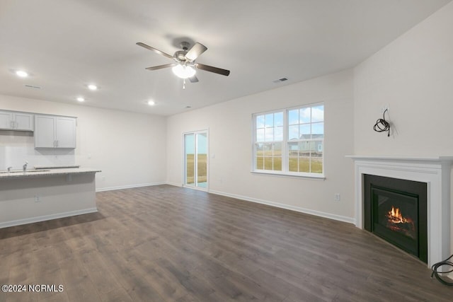 unfurnished living room featuring dark hardwood / wood-style floors, ceiling fan, and sink