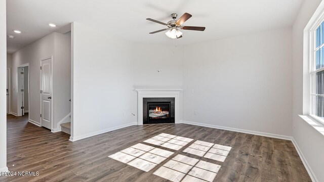 unfurnished living room featuring ceiling fan, dark hardwood / wood-style floors, and plenty of natural light