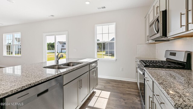 kitchen featuring light stone countertops, appliances with stainless steel finishes, dark wood-type flooring, and sink