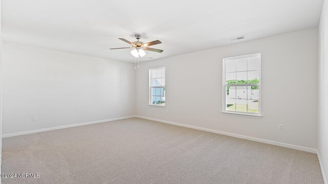 carpeted spare room featuring ceiling fan and plenty of natural light