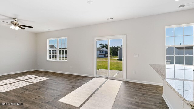 unfurnished room with ceiling fan, dark wood-type flooring, and a wealth of natural light