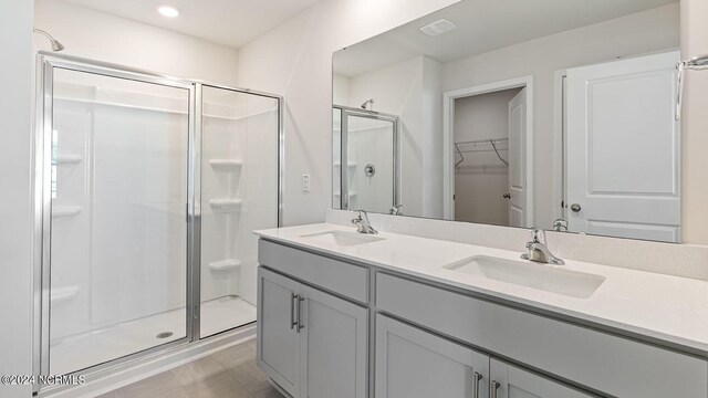 bathroom featuring a shower with door and vanity