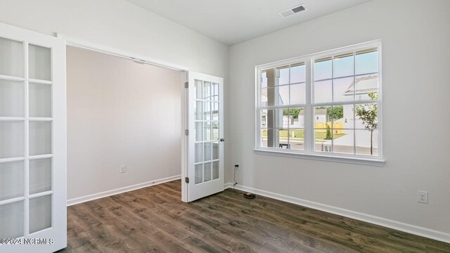 empty room with dark hardwood / wood-style floors, french doors, and a wealth of natural light