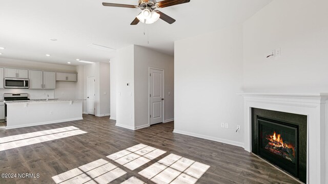 unfurnished living room featuring ceiling fan and dark hardwood / wood-style flooring