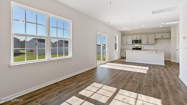 interior space featuring gray cabinets, a healthy amount of sunlight, a center island, and stainless steel appliances