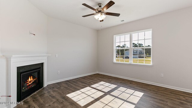 unfurnished living room featuring ceiling fan and dark wood-type flooring