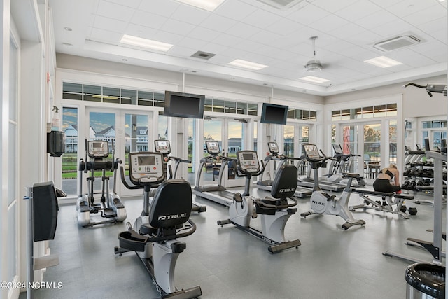 exercise room with a drop ceiling, a towering ceiling, and french doors