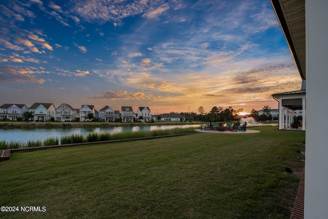 yard at dusk featuring a patio and a water view