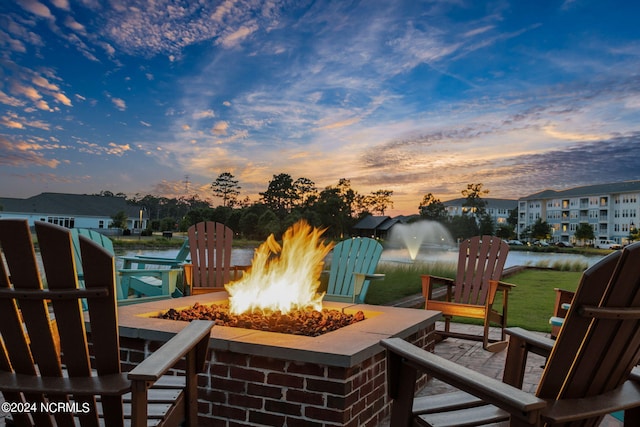 patio terrace at dusk with a water view and a fire pit