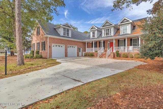 cape cod-style house featuring a garage and a porch