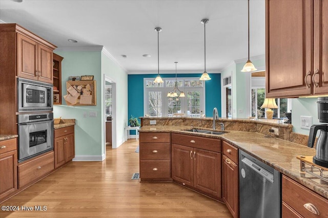 kitchen with light wood-type flooring, stainless steel appliances, hanging light fixtures, and sink