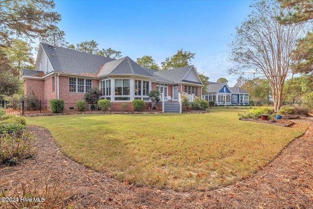 view of front of house featuring a sunroom and a front lawn