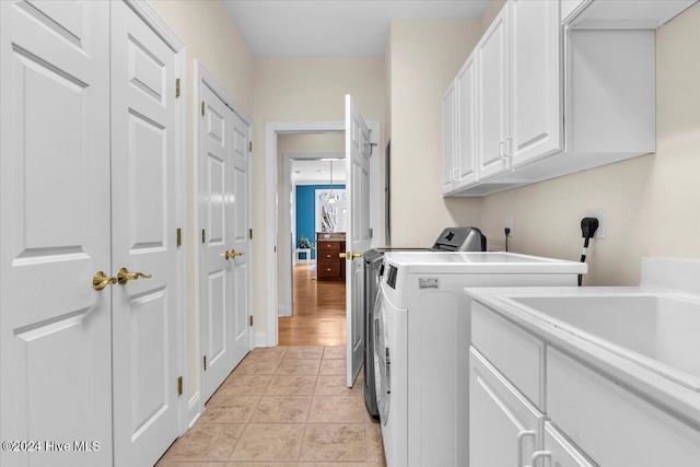 laundry room with cabinets, light tile patterned flooring, washer and dryer, and sink