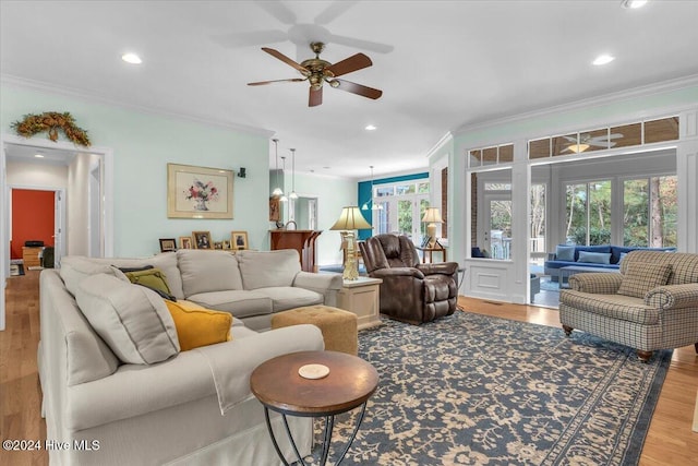 living room with ornamental molding, light wood-type flooring, a healthy amount of sunlight, and ceiling fan