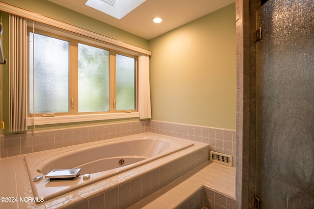 bathroom featuring tiled tub and a skylight