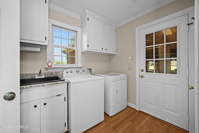 laundry area featuring washing machine and clothes dryer, ornamental molding, cabinets, and light wood-type flooring