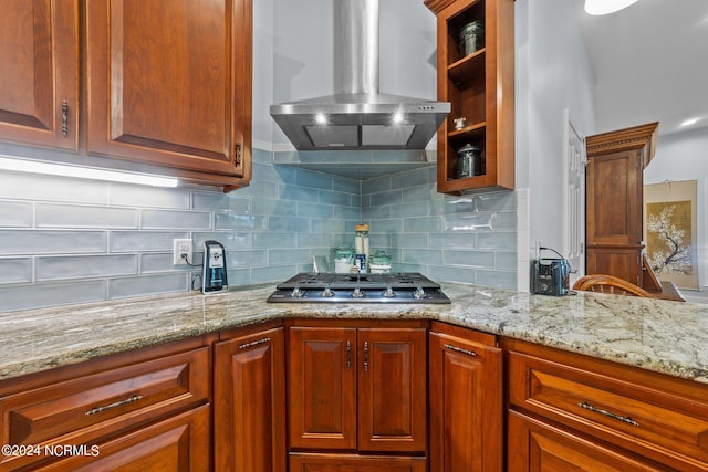 kitchen with wall chimney exhaust hood, stainless steel gas cooktop, light stone countertops, and tasteful backsplash