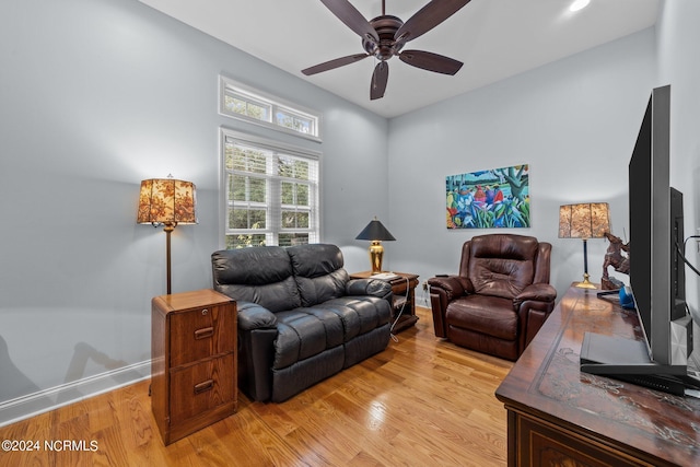 living area featuring ceiling fan, baseboards, and light wood-style floors