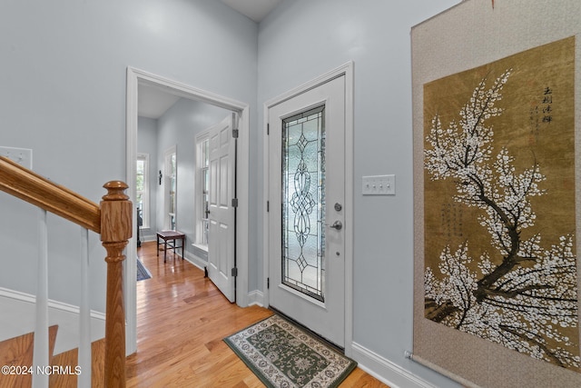 entrance foyer featuring light wood-type flooring, plenty of natural light, and baseboards