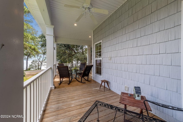 wooden terrace with a ceiling fan and outdoor dining space