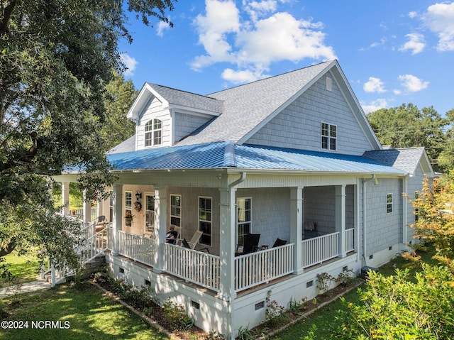 back of house with a porch, crawl space, roof with shingles, and metal roof