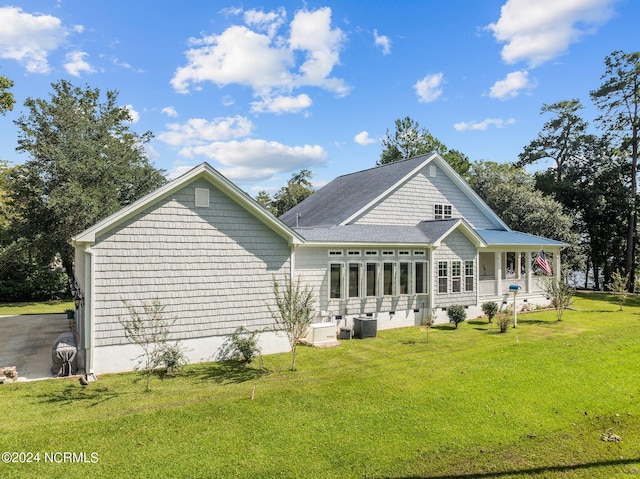 rear view of house featuring a porch, a lawn, and central AC